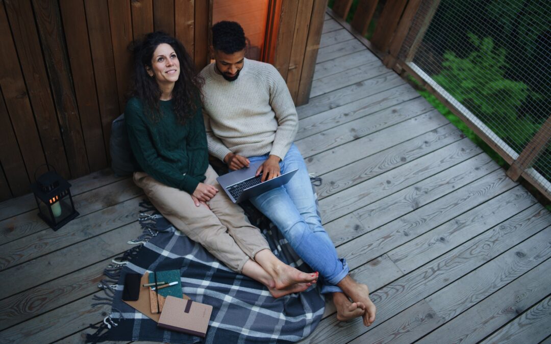 Couple with laptop resting outdoors in a tree house, weekend away and remote office concept.