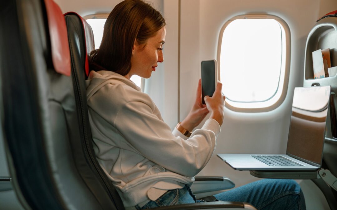 Young woman taking picture with smartphone in airplane